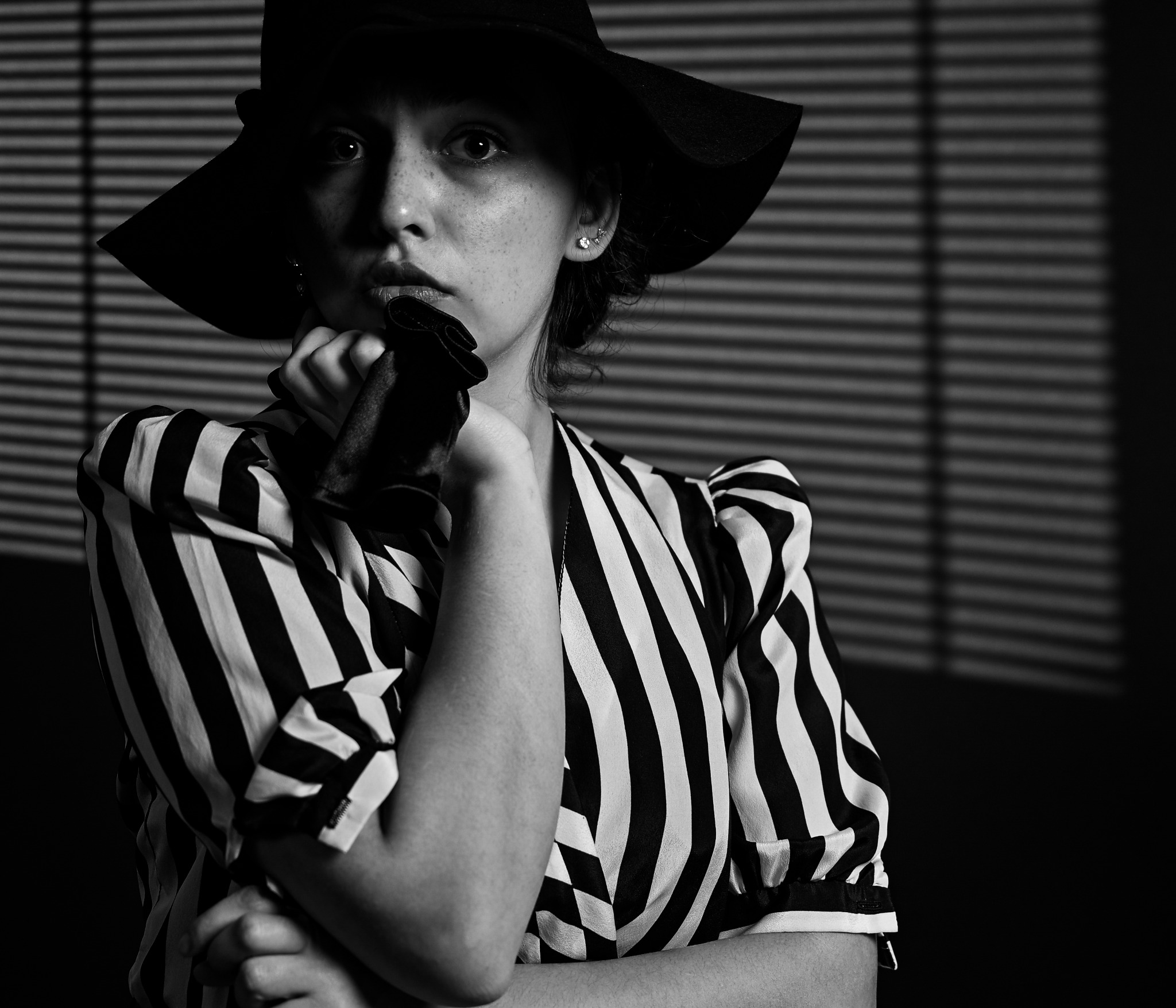 Black-and-white noir portrait with a wide-brimmed hat and striped jacket